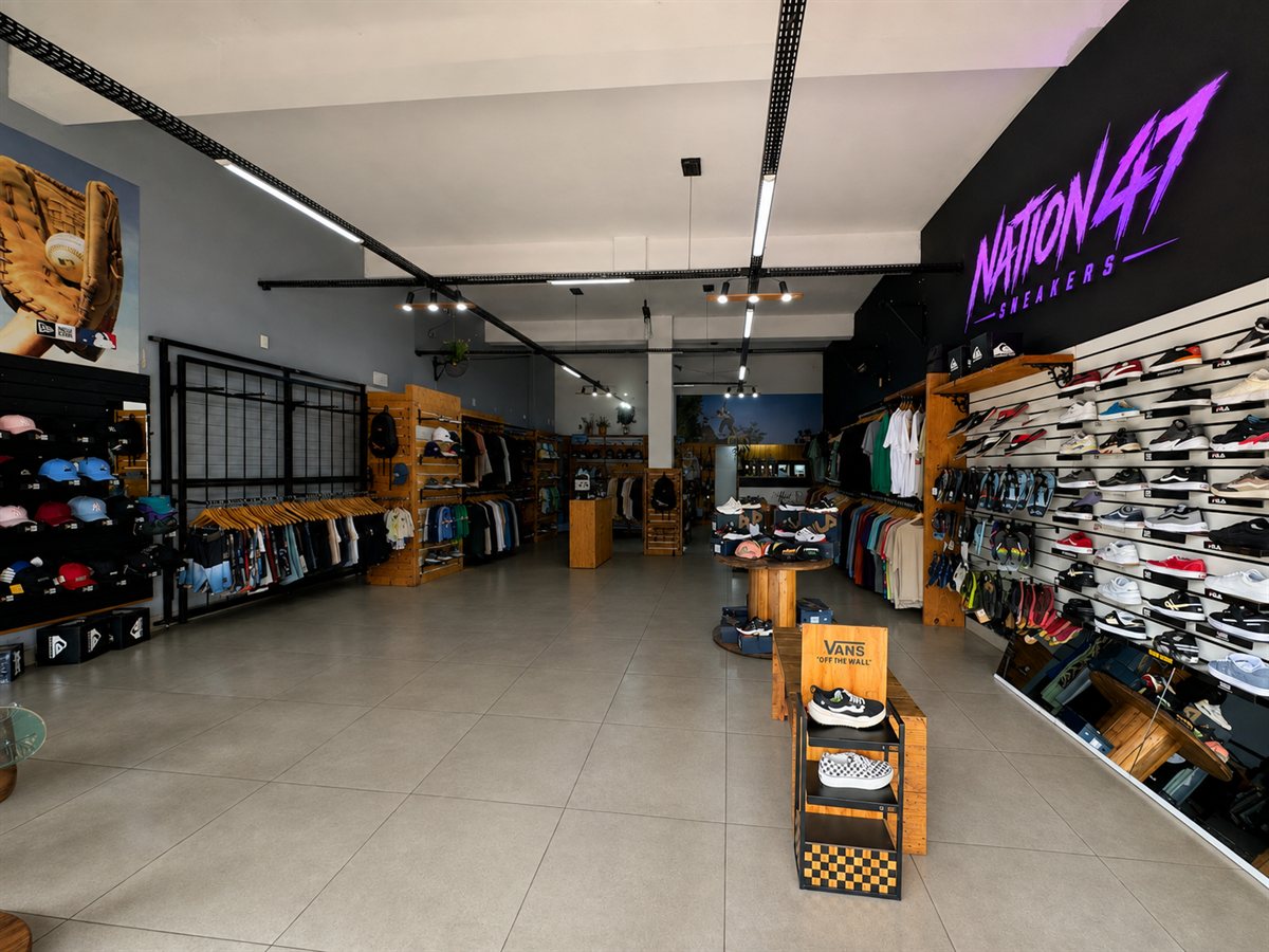Interior da loja Nation 47 Sneakers, com a parede de tênis e o letreiro da marca